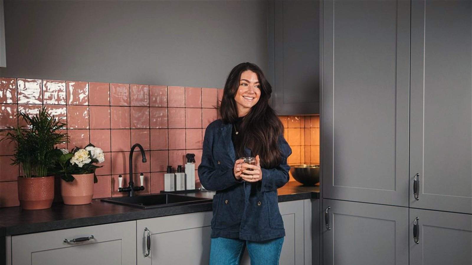 Grijze keuken met roze tegelwand, waar gewoon geleefd wordt